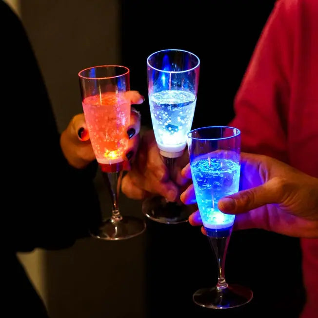 Flûtes lumineuses à LED tenues en main. Idéales pour un toast de fête ou un événement de fin d’année original.