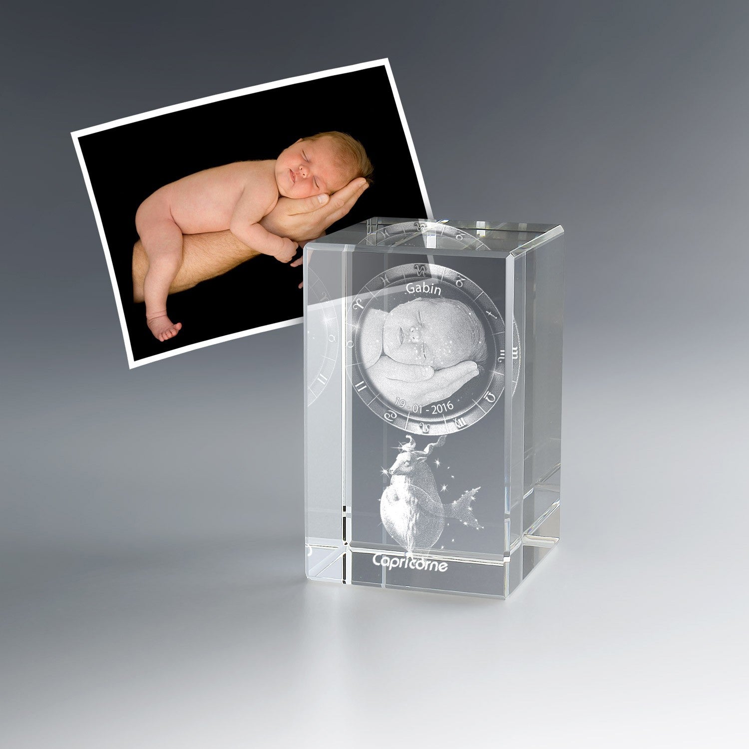 Photo de bébé endormi gravée en 3D dans un bloc de verre vertical avec signe du zodiaque Capricorne, prénom et date. Un cadeau de naissance personnalisé inoubliable.