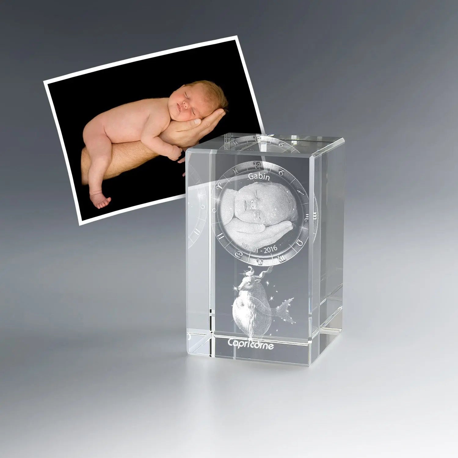 Photo de bébé endormi gravée en 3D dans un bloc de verre vertical avec signe du zodiaque Capricorne, prénom et date. Un cadeau de naissance personnalisé inoubliable.