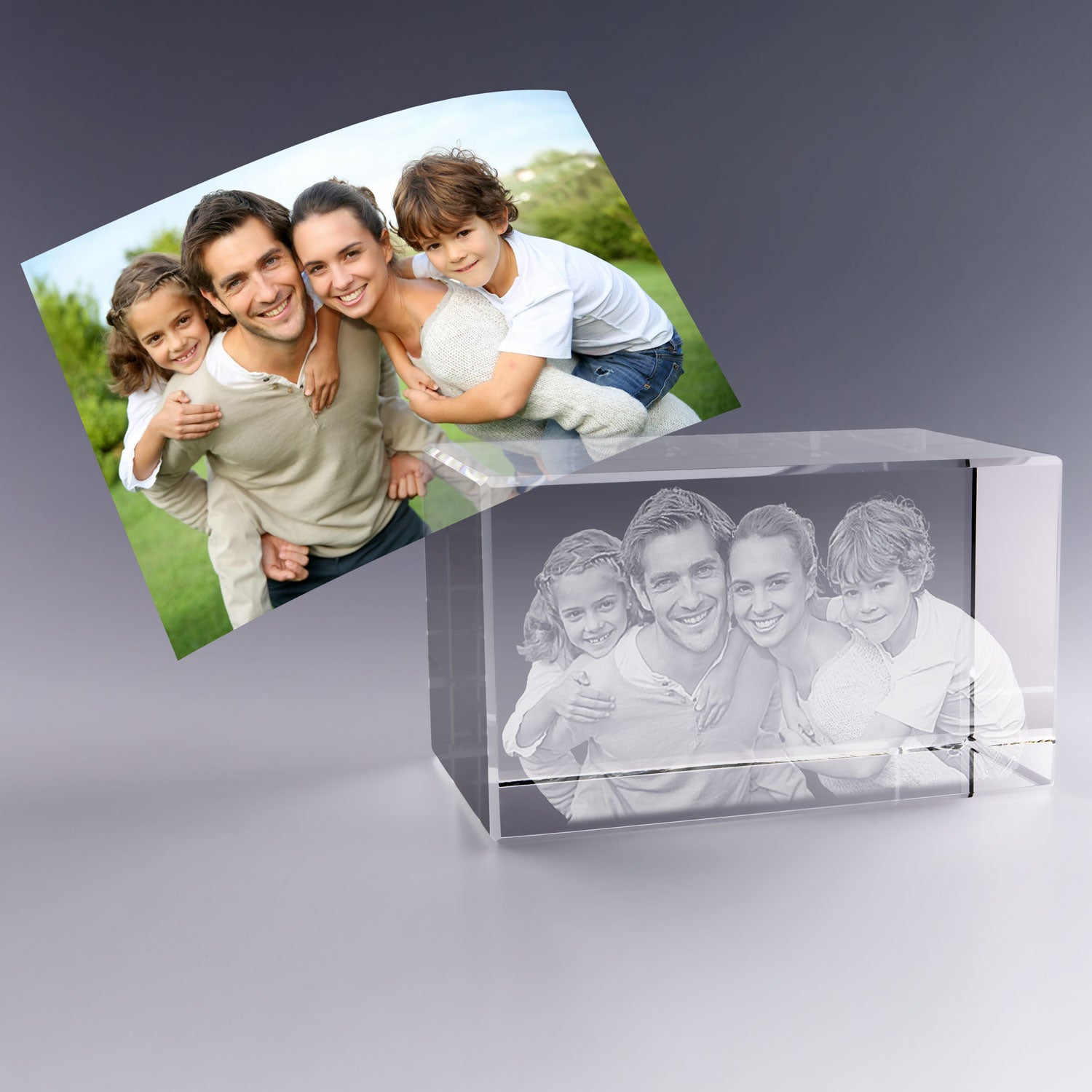 Bloc en verre horizontal de 12 cm gravé en 3D avec le portrait d’une famille de quatre personnes, inspiré de la photo couleur placée en arrière-plan.