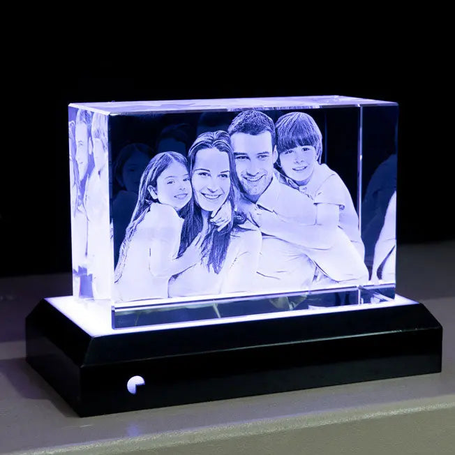 Bloc en verre gravé en 3D avec le portrait d’une famille, posé sur un socle lumineux éclairage blanc qui met en valeur les détails de la gravure.