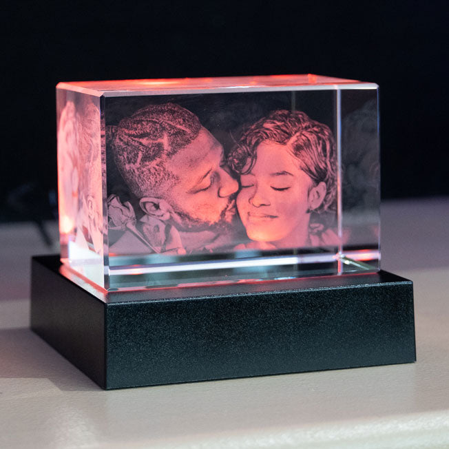 Bloc en verre gravé en 3D avec le même couple complice, mis en valeur par un socle lumineux à éclairage rouge chaud et romantique.