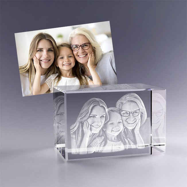 Bloc en verre gravé en 3D avec le portrait d’une grand-mère, sa fille et sa petite-fille souriantes, inspiré d’une photo familiale lumineuse.