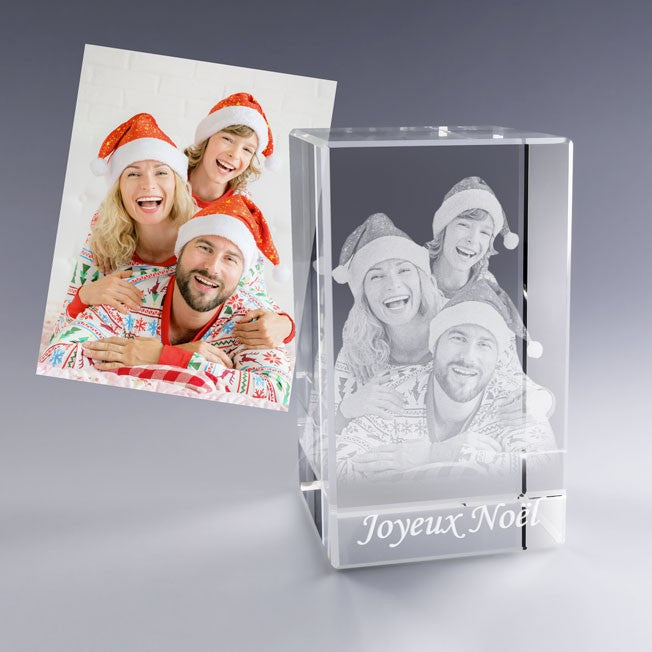 Bloc en verre vertical personnalisé représentant une famille souriante en tenues de Noël avec bonnets rouges. La photo gravée montre trois visages heureux superposés, accompagnés de la mention "Joyeux Noël", parfaite pour un souvenir festif et chaleureux.