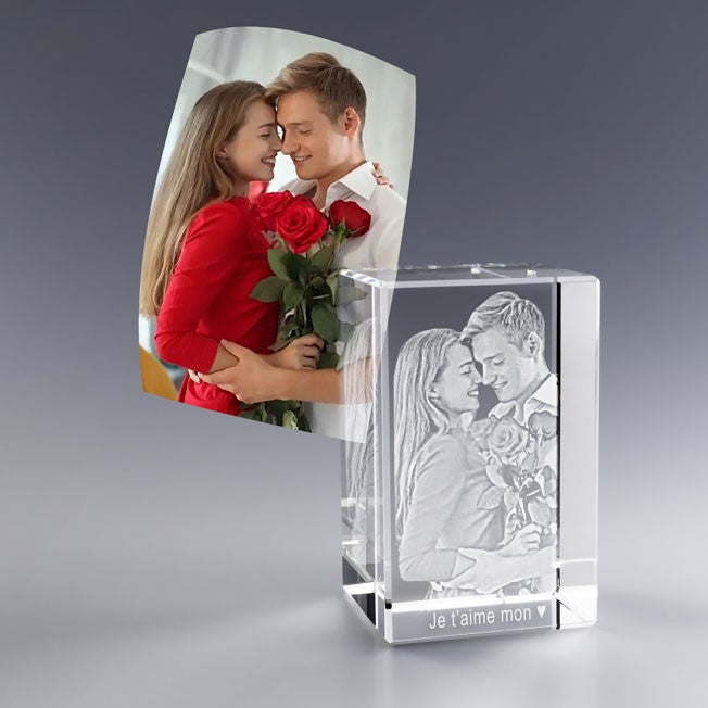 Bloc en verre gravé 3D représentant un couple enlacé, la femme tenant un bouquet de roses rouges. Cadeau romantique parfait pour la Saint-Valentin ou un anniversaire de rencontre. Gravure laser personnalisée sur cristal pour un souvenir éternel.
