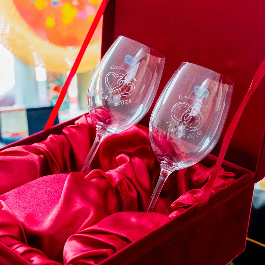 Coffret de deux verres à vin gravés avec prénoms et date, idéal comme cadeau personnalisé pour mariage ou anniversaire. Présentés dans un écrin rouge en satin.