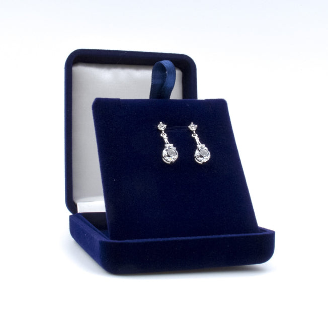 Boucles d’oreilles argentées avec pendentif Tour Eiffel et cristaux Swarovski®, présentées dans un écrin personnalisable pour un cadeau raffiné.