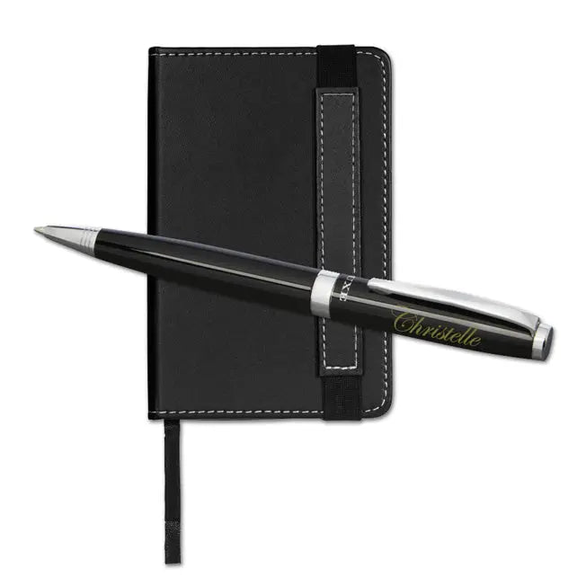 Stylo personnalisé noir posé sur un petit carnet noir avec surpiqûres blanches, formant un ensemble élégant et pratique à offrir en cadeau.