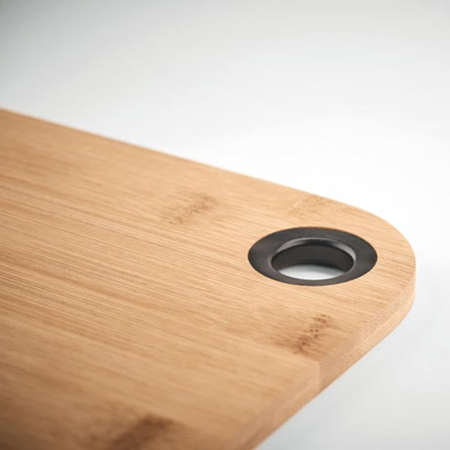 Gros plan sur une planche à découper en bambou personnalisable, avec trou d’accroche cerclé de noir, idéale pour un cadeau personnalisé.