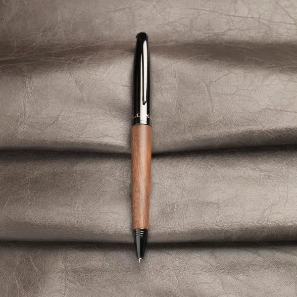 Stylo à bille avec corps en bois posé sur fond cuir, cadeau personnalisable élégant pour professionnels et particuliers.