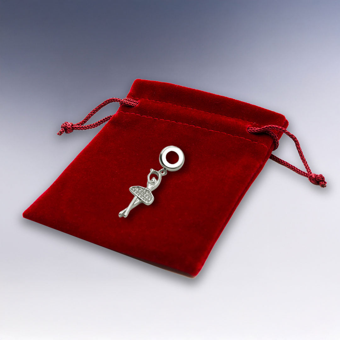 Charm Ballerine argenté délicat, posé sur une pochette en velours rouge. Idéal comme cadeau élégant pour les amatrices de ballet ou de bijoux fins.