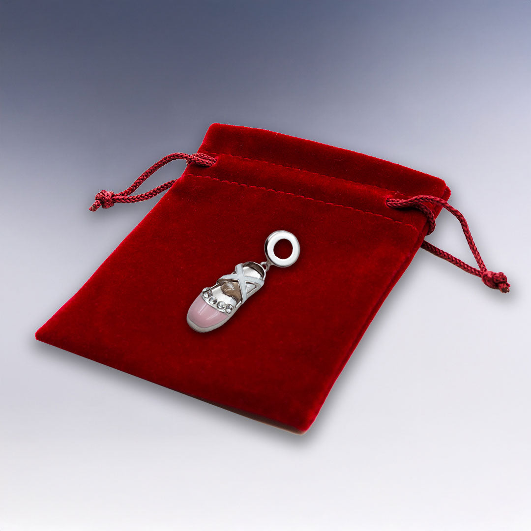Charm ballerine en métal argenté, décoré de cristaux et présenté sur un élégant pochon rouge. Idéal pour un bracelet à personnaliser avec style.