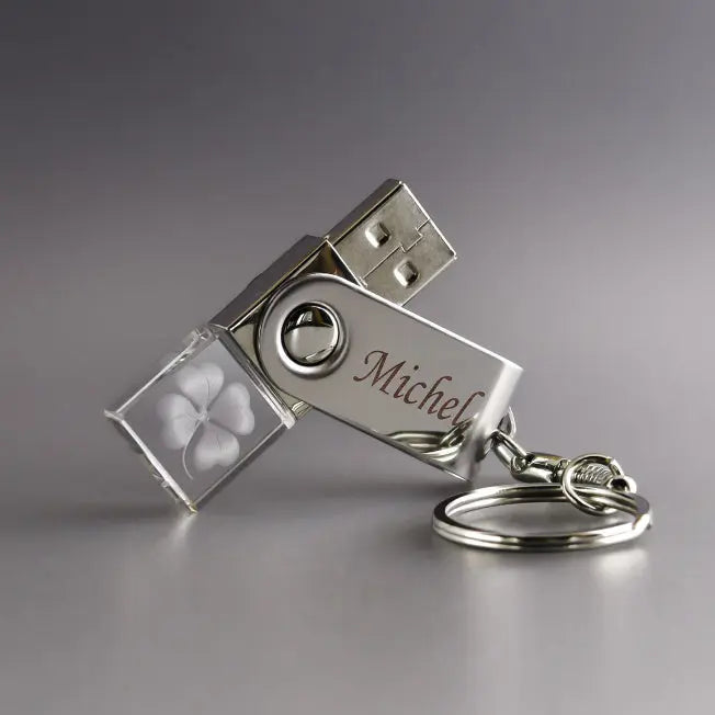 Clé USB 32 Go avec corps en verre transparent gravé d’un trèfle à 4 feuilles et partie métallique personnalisée avec le prénom “Michel”, montée sur un porte-clés.