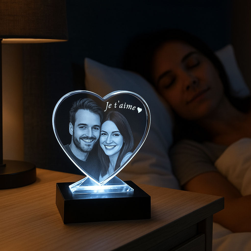 Bloc cœur en verre avec gravure 2D “Je t’aime” et portrait de couple, posé sur un socle lumineux. Cadeau original à offrir pour un moment spécial à deux.