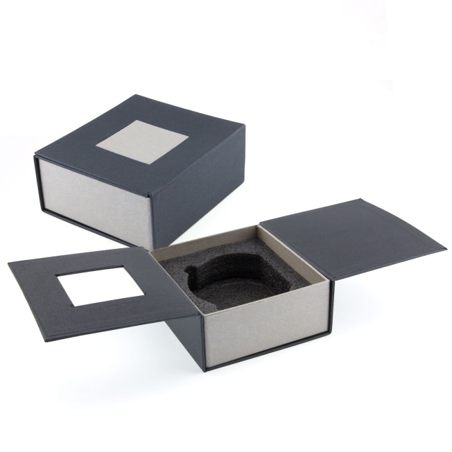 Boîte rigide noire et grise avec mousse de calage, spécialement conçue pour protéger un bloc en verre demi-lune gravé en 3D.