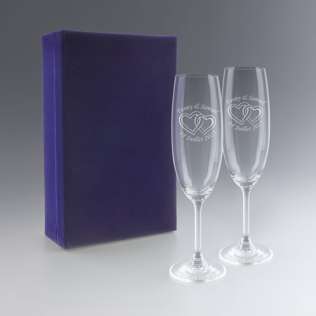 Deux flûtes à champagne gravées avec prénoms, date et motif cœurs, présentées dans un coffret bleu. Un cadeau personnalisé parfait pour un mariage d’hiver.