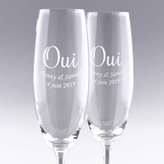 Duo de flûtes à champagne gravées "OUI" avec prénoms et date. Cadeau de mariage personnalisé parfait pour célébrer l’union des mariés avec élégance.