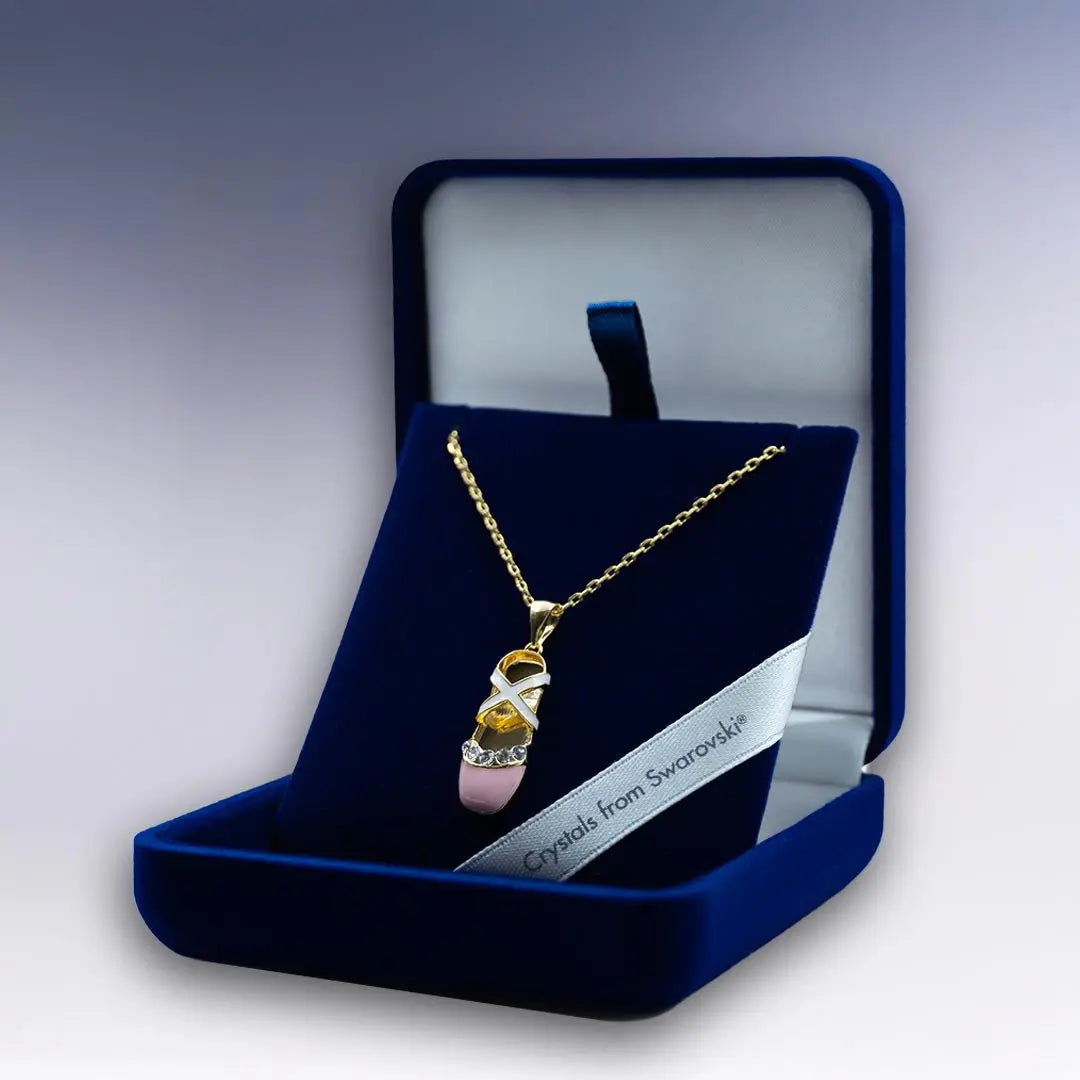 Pendentif doré en forme de chausson de danse classique, décoré de cristaux Swarovski®, mis en valeur dans un coffret cadeau luxueux.
