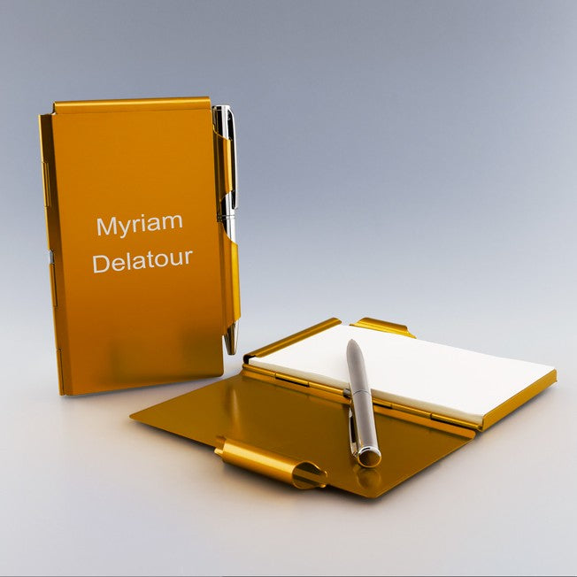 Bloc-notes en métal orange personnalisable avec stylo argent, gravé au nom « Myriam Delatour », idéal pour cadeau unique.