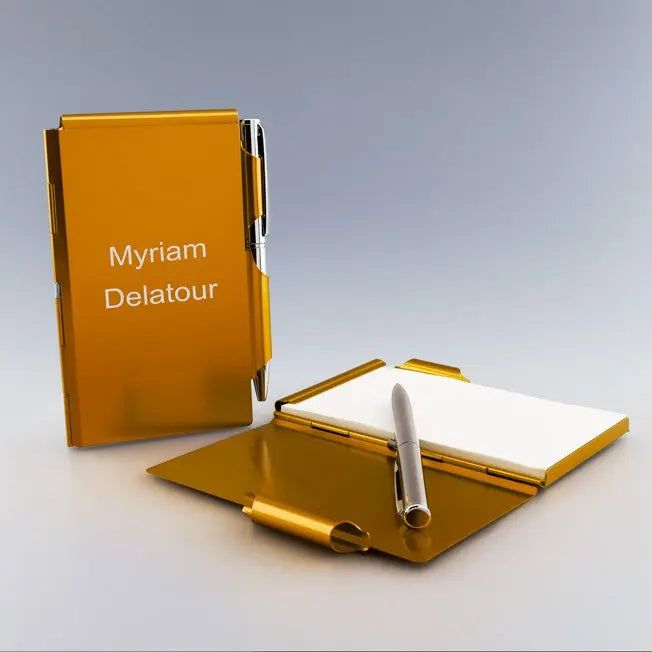 Bloc-notes en métal orange personnalisable avec stylo argent, gravé au nom « Myriam Delatour », idéal pour cadeau unique.