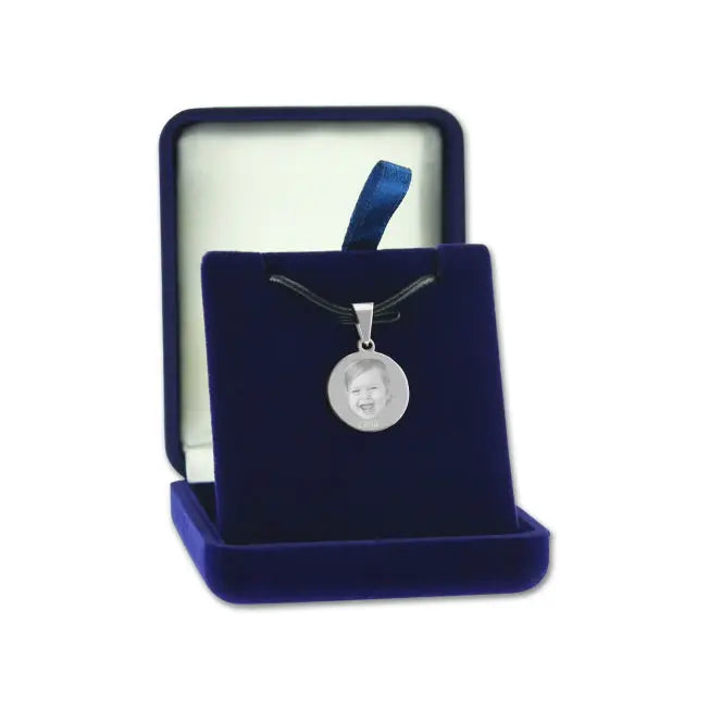 Pendentif rond en métal argenté avec photo gravée, présenté dans un écrin bleu – un cadeau personnalisé plein d’émotion.