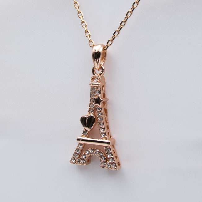 Gros plan sur pendentif Tour Eiffel Cœur finition or rose, décoré d’un cœur et d’une étoile, avec cristaux lumineux.