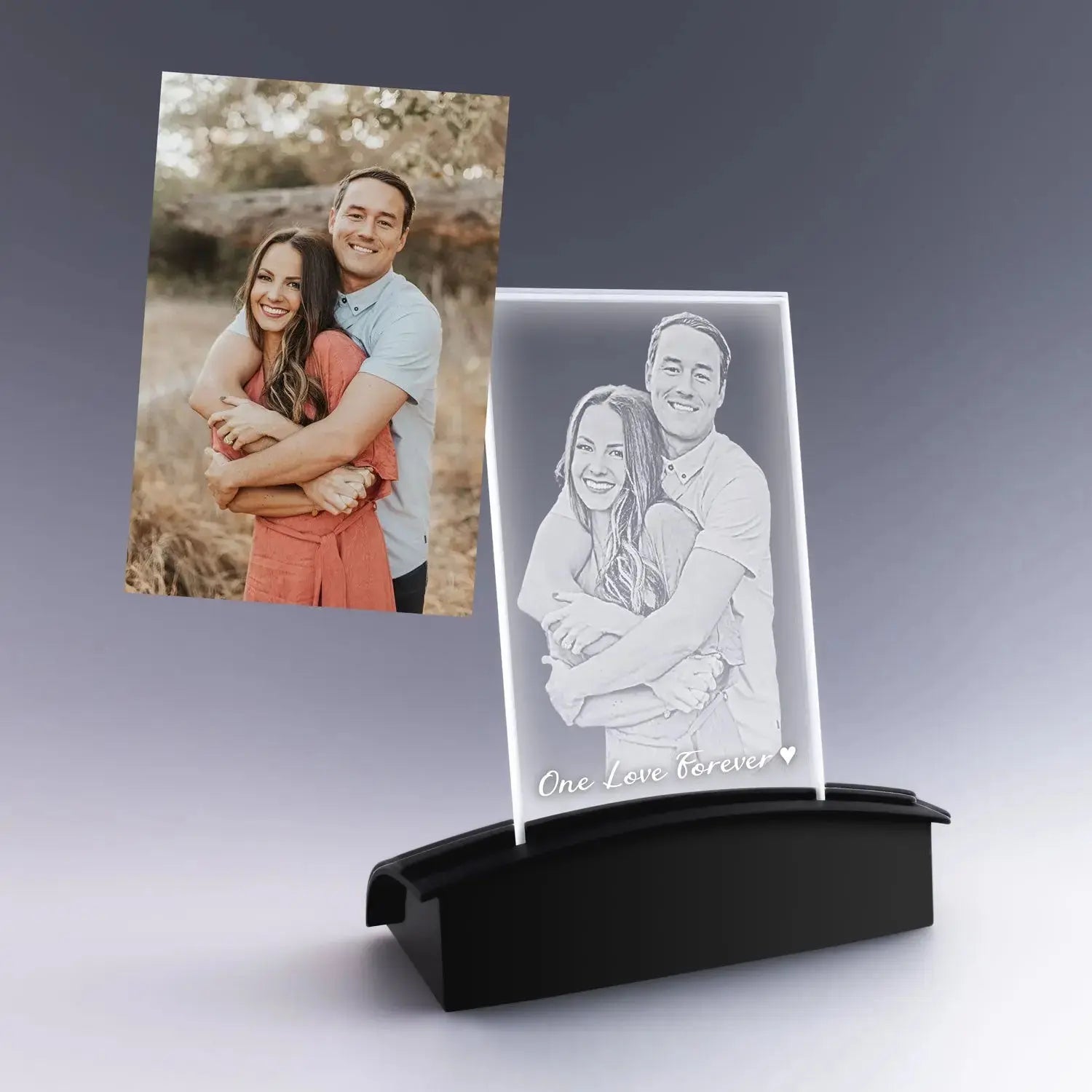 Gravure 2D personnalisée d’un couple enlacé sur plaque photo verticale en verre, posée sur un socle lumineux noir, cadeau romantique élégant.