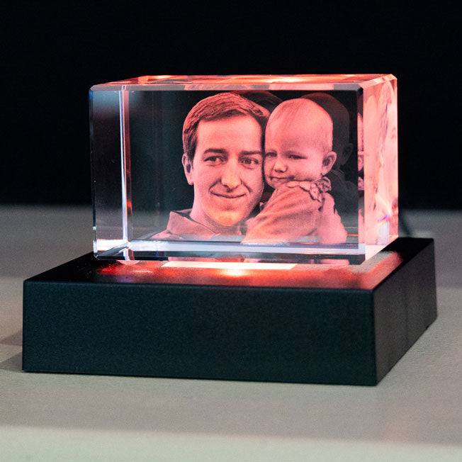 Bloc Verre avec Père et Bébé sur Socle Rouge – Bloc photo gravé représentant un père et son enfant, posé sur un socle carré lumineux à LED rouges pour un effet chaleureux.