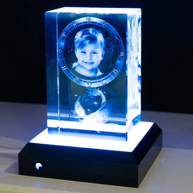 Un grand bloc en verre gravé 3D, illuminé par une lumière blanche intense du socle interactif carré, dévoile les détails avec éclat et finesse.