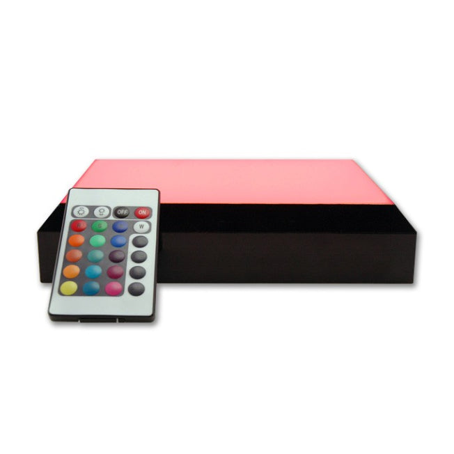 Socle lumineux interactif avec éclairage rouge et télécommande multifonction. Il est conçu pour valoriser les blocs photo en verre dans une atmosphère chaleureuse.