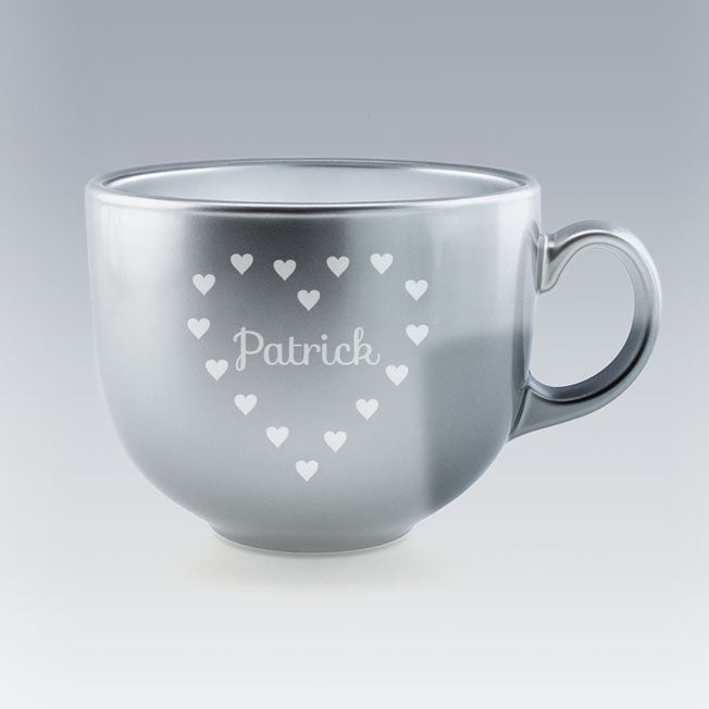 Tasse Jumbo argentée avec le prénom "Patrick" gravé au centre d’un motif en forme de cœur composé de petits cœurs blancs, sur fond clair dégradé.