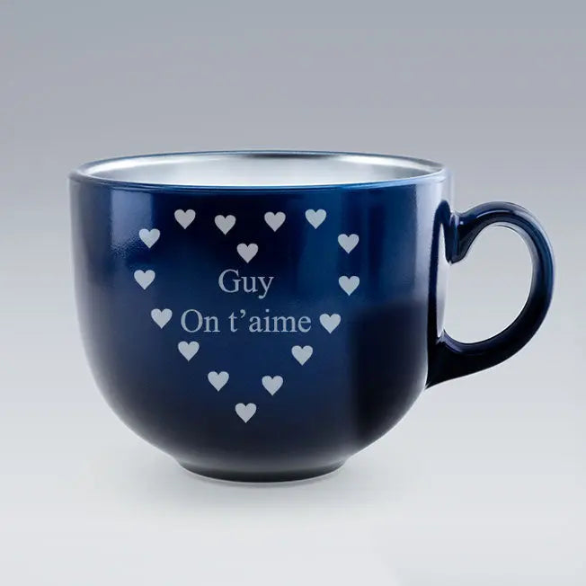 Tasse Jumbo bleue personnalisée avec le texte "Guy On t’aime", gravé au centre d’un cœur formé de petits cœurs, sur fond uni gris.