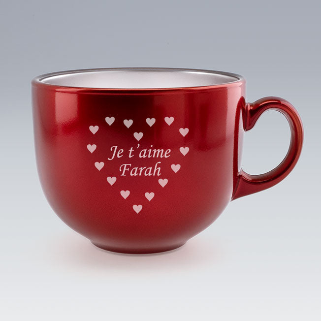 Gros plan d’une tasse Jumbo rouge brillante avec la gravure "Je t’aime Farah" entourée de petits cœurs disposés en forme de cœur.