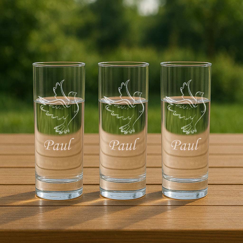 Trois verres à eau personnalisés avec une colombe en vol et le prénom Paul, posés sur une table extérieure, idéal pour un moment de partage en plein air.