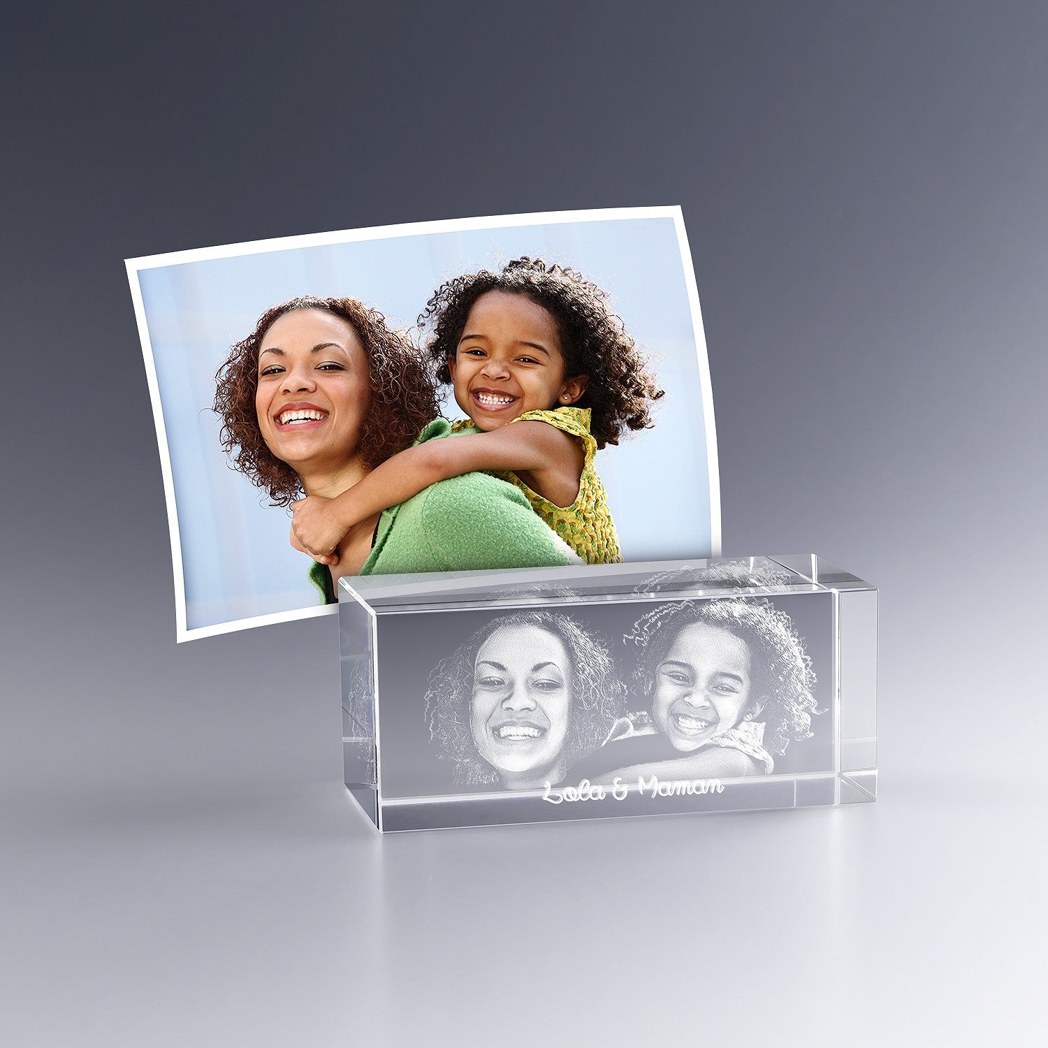 Bloc en verre gravé en 3D avec le portrait d’une mère et de sa fille souriantes, accompagné de l’inscription “Lola & Maman”, d’après une photo couleur.