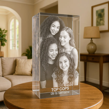 Bloc en verre vertical de 30 cm gravé en 3D avec cinq amies souriantes et l’inscription “TOP COP’S de la semaine”, posé sur une table dans un salon.
