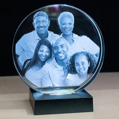 Bloc rond gravé en verre avec photo de famille, présenté sur socle à LED. Cadeau personnalisé à offrir pour les grandes occasions ou la décoration maison.