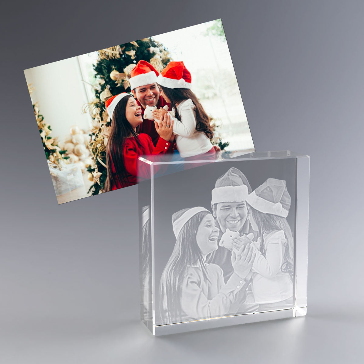 Bloc en Verre Square 3D avec photo de Noël gravée – Une famille souriante porte des bonnets rouges devant un sapin de Noël. Le souvenir est immortalisé dans un bloc en verre gravé en 3D, symbole d’un cadeau personnalisé élégant et lumineux à offrir pour les fêtes.