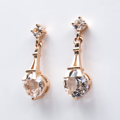 Boucles d’oreilles pendantes en or rose, avec cristaux Swarovski® sertis sous une Tour Eiffel stylisée. Bijou romantique et lumineux.