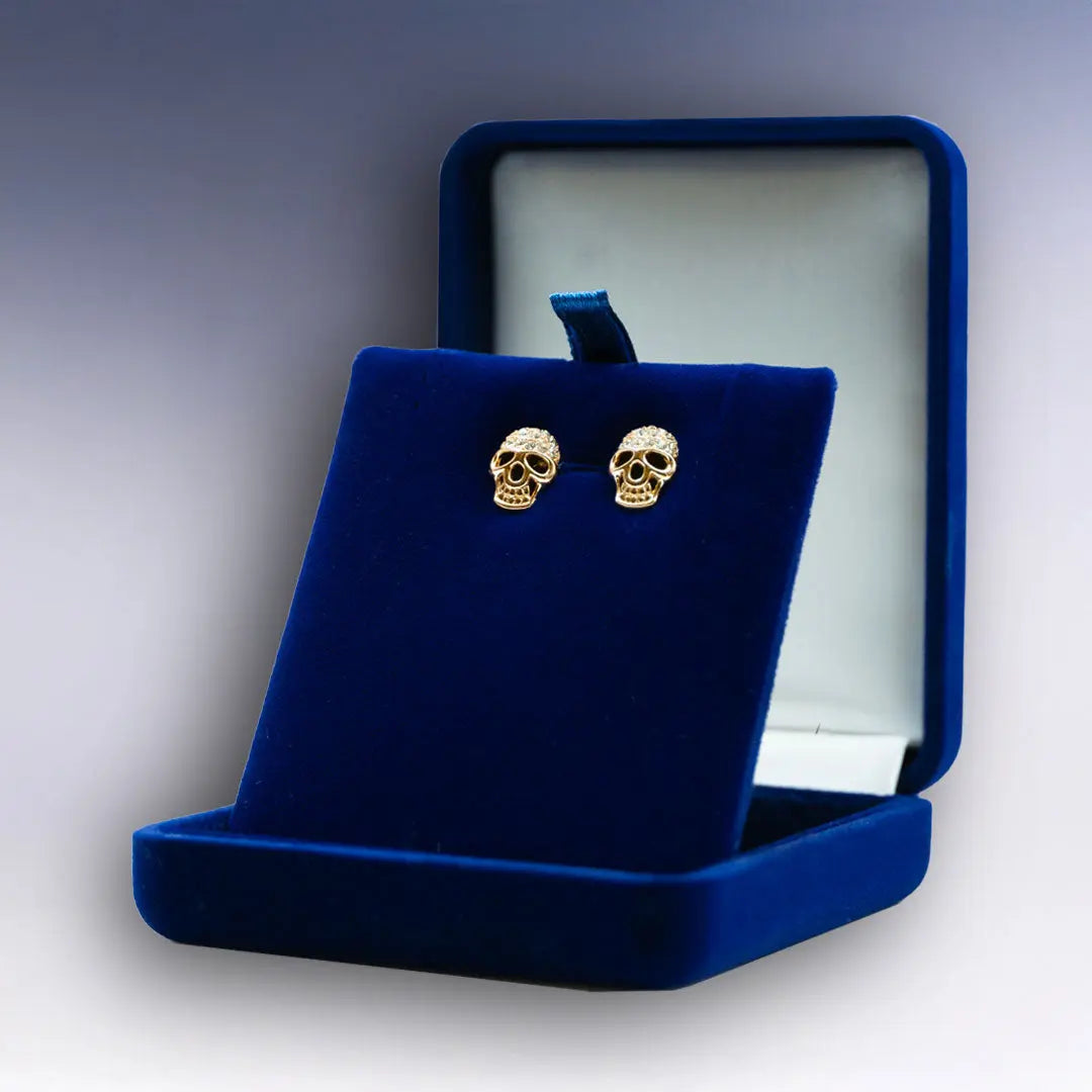 Élégantes boucles d’oreilles dorées Tête de Mort avec détails scintillants, proposées dans un coffret bleu que vous pouvez personnaliser à souhait.