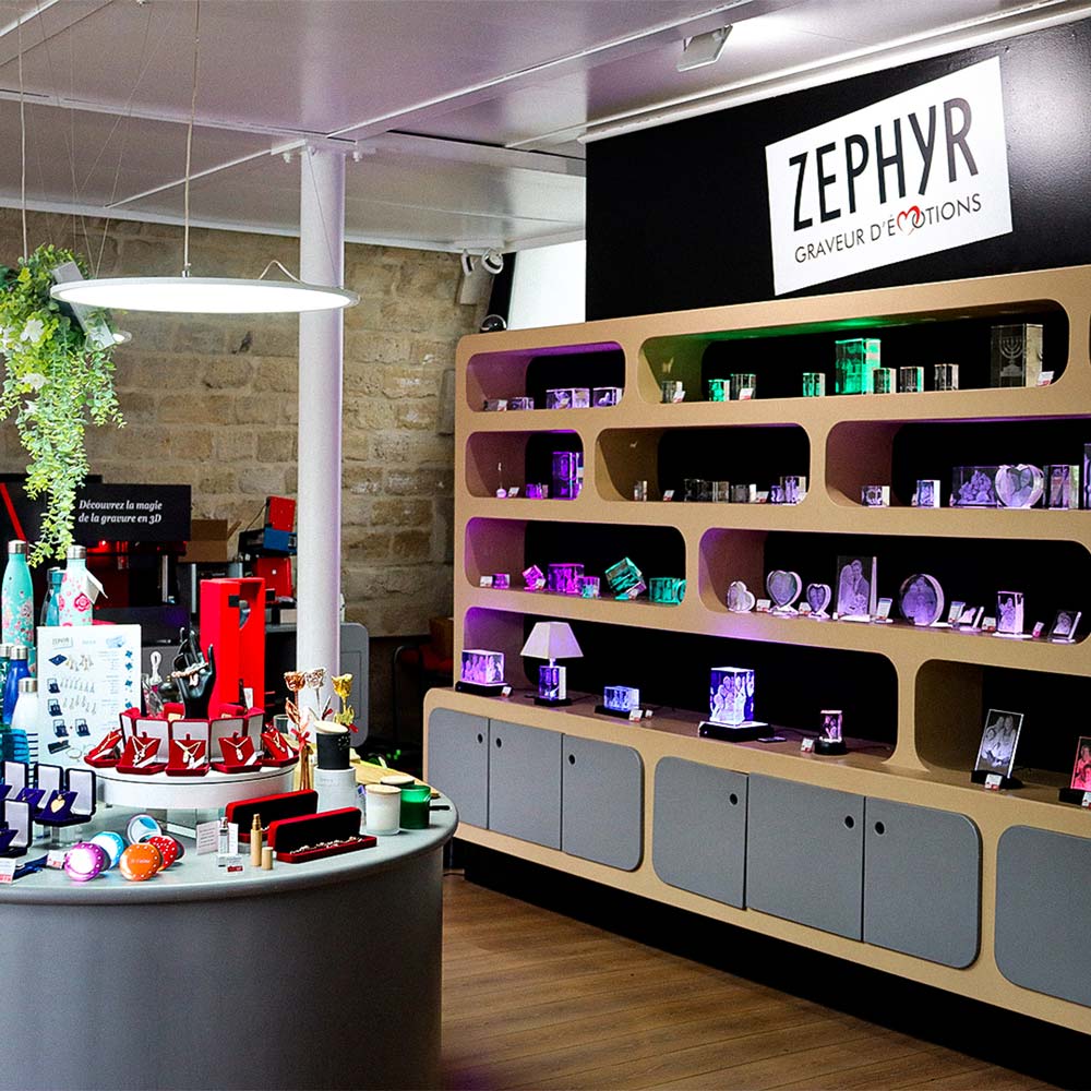 Intérieur de la boutique Zephyr Paris avec blocs en verre gravés, objets personnalisés et socles lumineux exposés sur des étagères rétroéclairées.