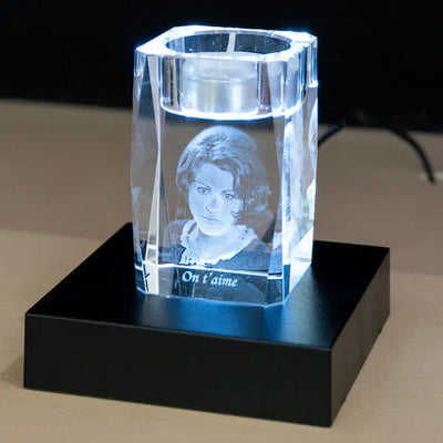 Bougeoir en verre gravé en 3D avec le portrait d’une femme et le message "On t’aime", posé sur un socle lumineux noir.