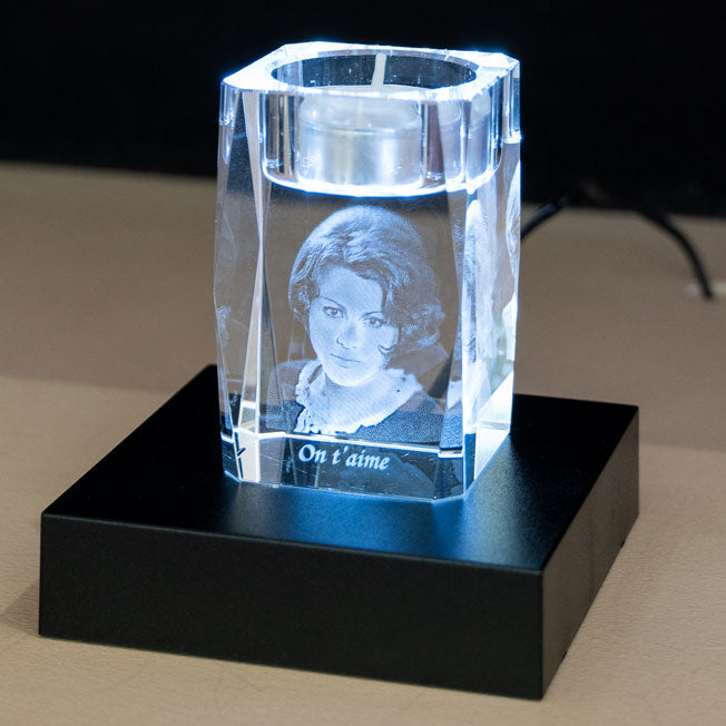 Bougeoir en verre gravé en 3D avec le portrait d’une femme et le message "On t’aime", posé sur un socle lumineux noir.