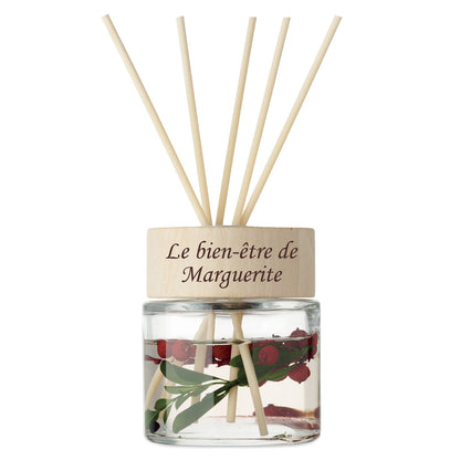 Diffuseur de parfum en verre avec gravure personnalisée “Le bien-être de Marguerite”, contenant fleurs séchées et bâtonnets en bois naturel.