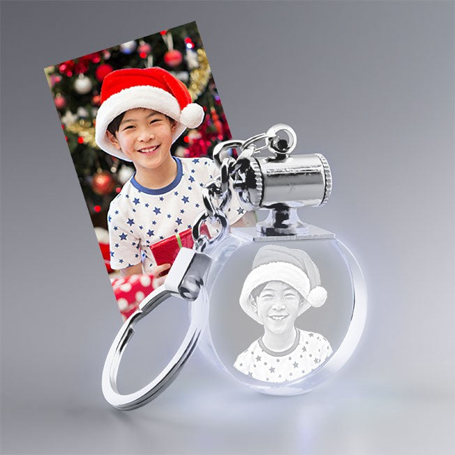 Porte-clés lumineux personnalisé avec la photo 2D d’un enfant à Noël. Gravure sur verre ronde idéale pour un cadeau festif.