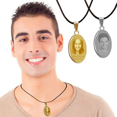 Homme souriant portant un pendentif ovale doré personnalisé avec photo, accompagné des versions or et argent suspendues sur cordons noirs en arrière-plan.