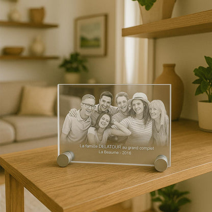Plaque photo horizontale en verre gravée en 2D posée sur un meuble, représentant une famille réunie, texte “La famille DELATOUR au grand complet - La Beaume 2016” visible.