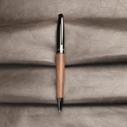 Stylo à bille avec corps en bois posé sur fond cuir, cadeau personnalisable élégant pour professionnels et particuliers.