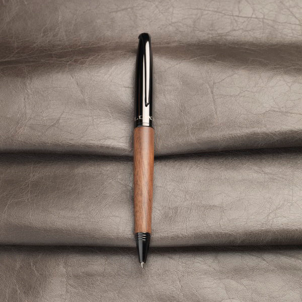 Stylo à bille avec corps en bois posé sur fond cuir, cadeau personnalisable élégant pour professionnels et particuliers.