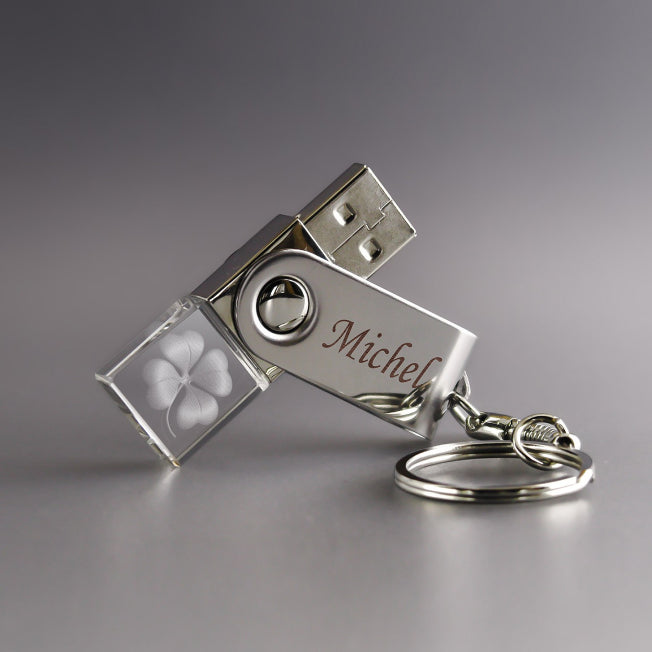 Clé USB 32 Go avec corps en verre transparent gravé d’un trèfle à 4 feuilles et partie métallique personnalisée avec le prénom “Michel”, montée sur un porte-clés.